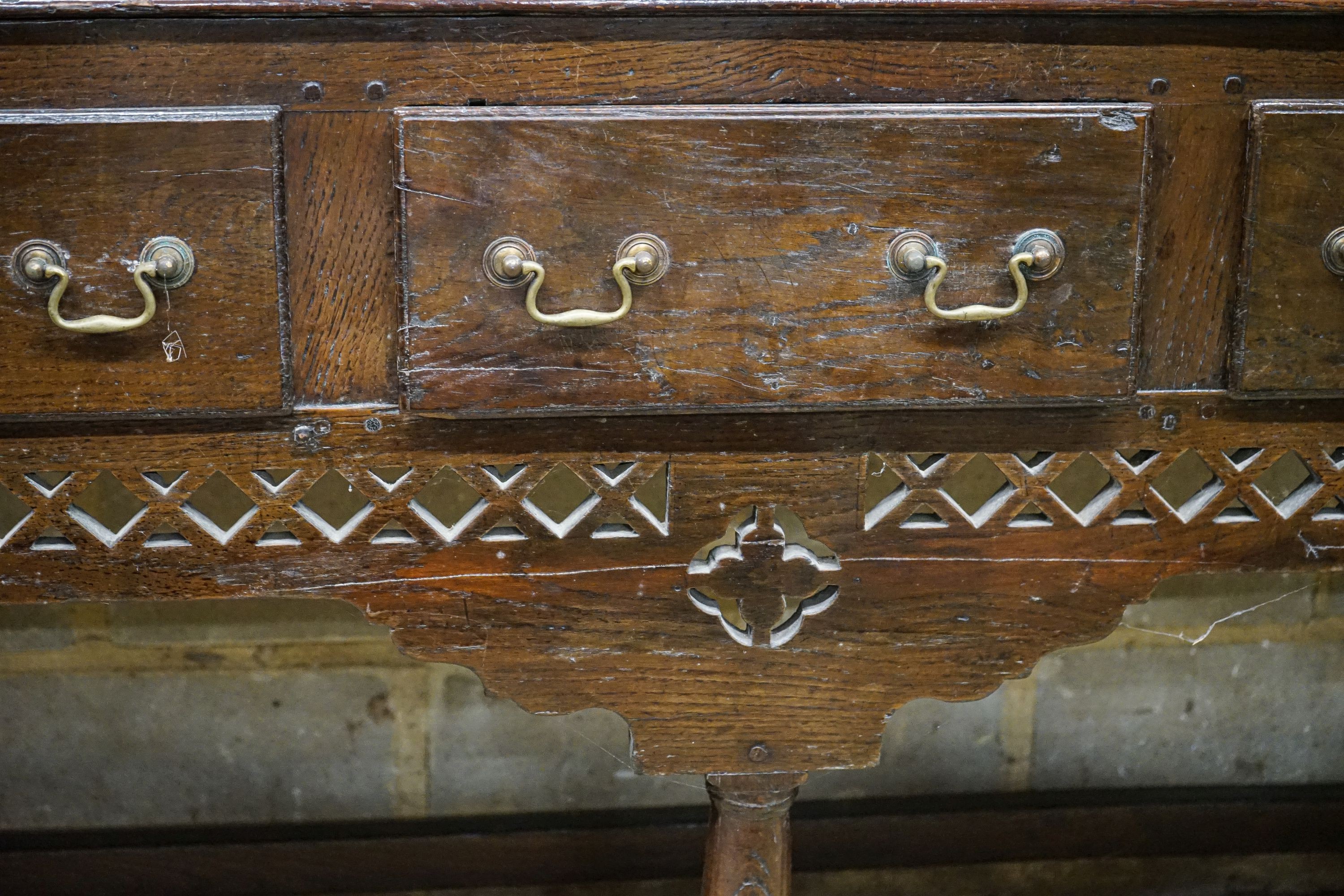 A mid 18th century oak dresser, with pierced cornice and three shelf rack over three drawers, with pierced frieze and turned and squared underframe, width 142cm, depth 46cm, height 204cm